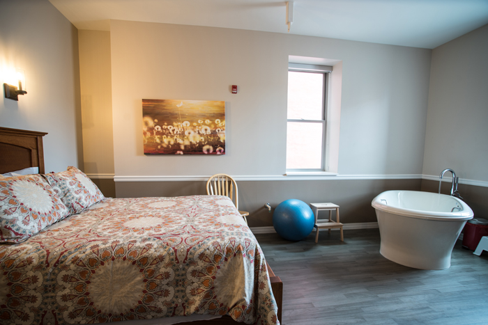 The Midwife Center's Meadow Room birth suite and birth tub. The birth suite is decorated in orange, tan, and red colors.