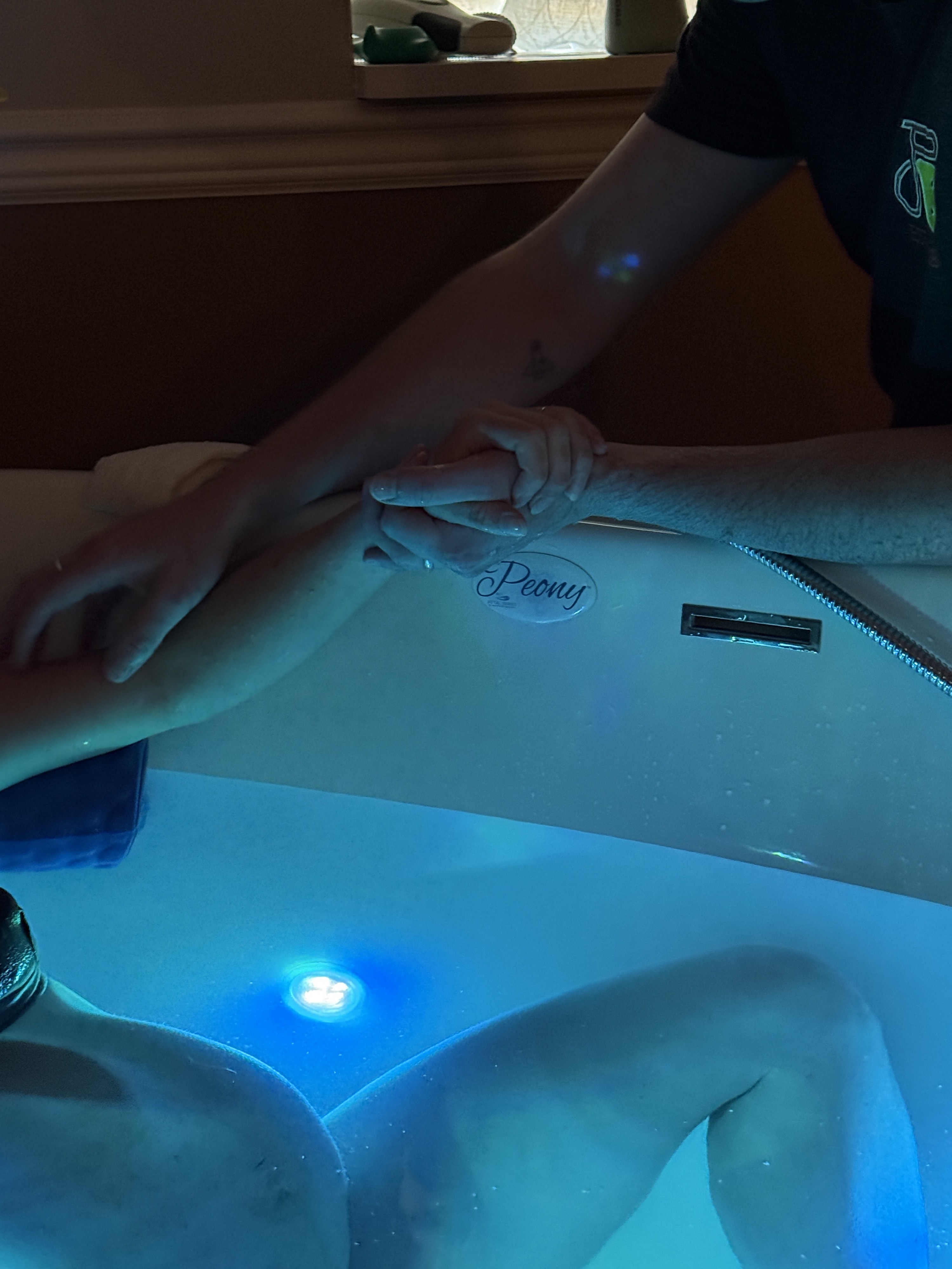 Mackenzie and Finn hold hands while she labors in the tub.