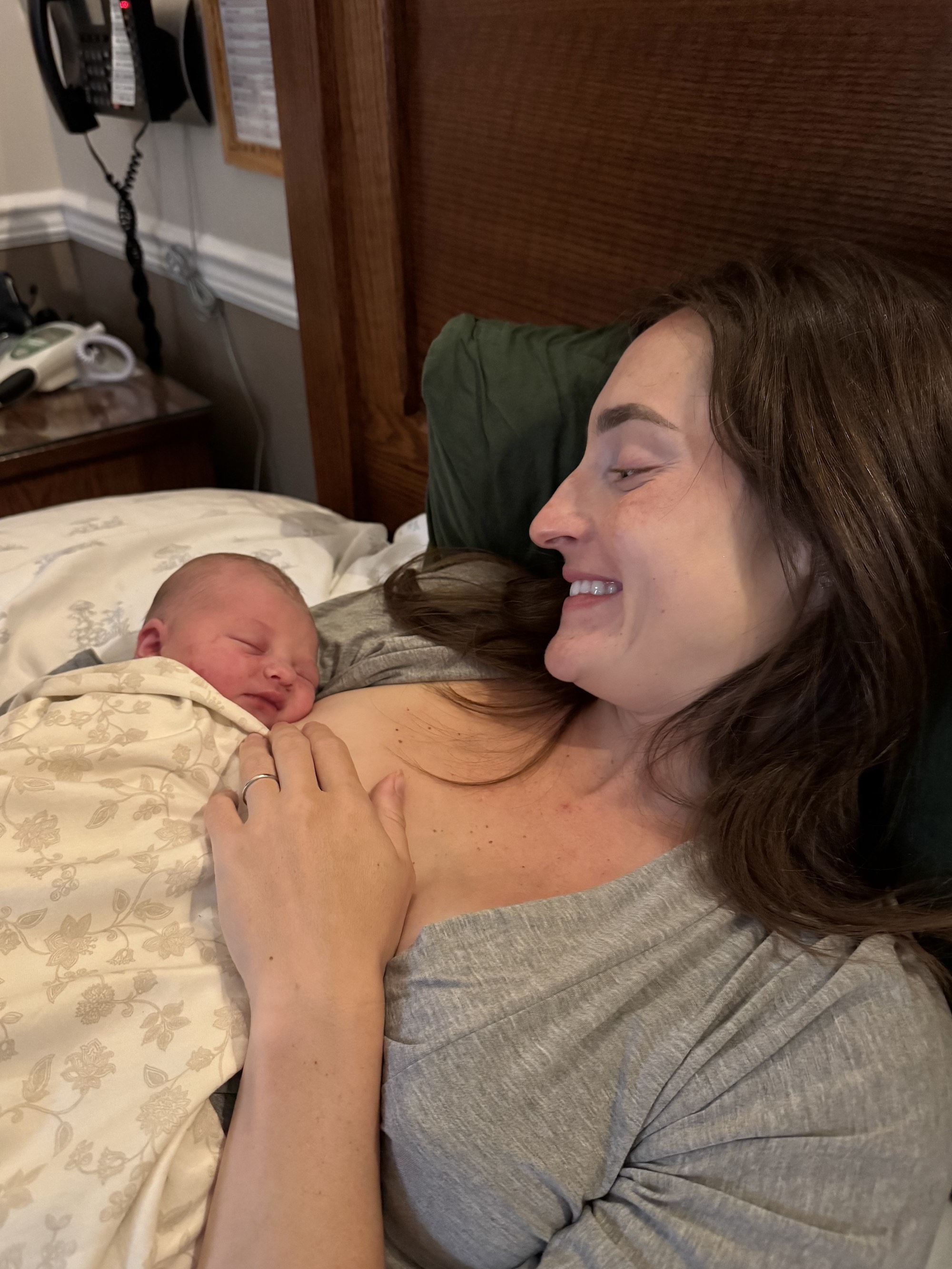 Mackenzie rests on the bed, smiling at Helena on her chest.